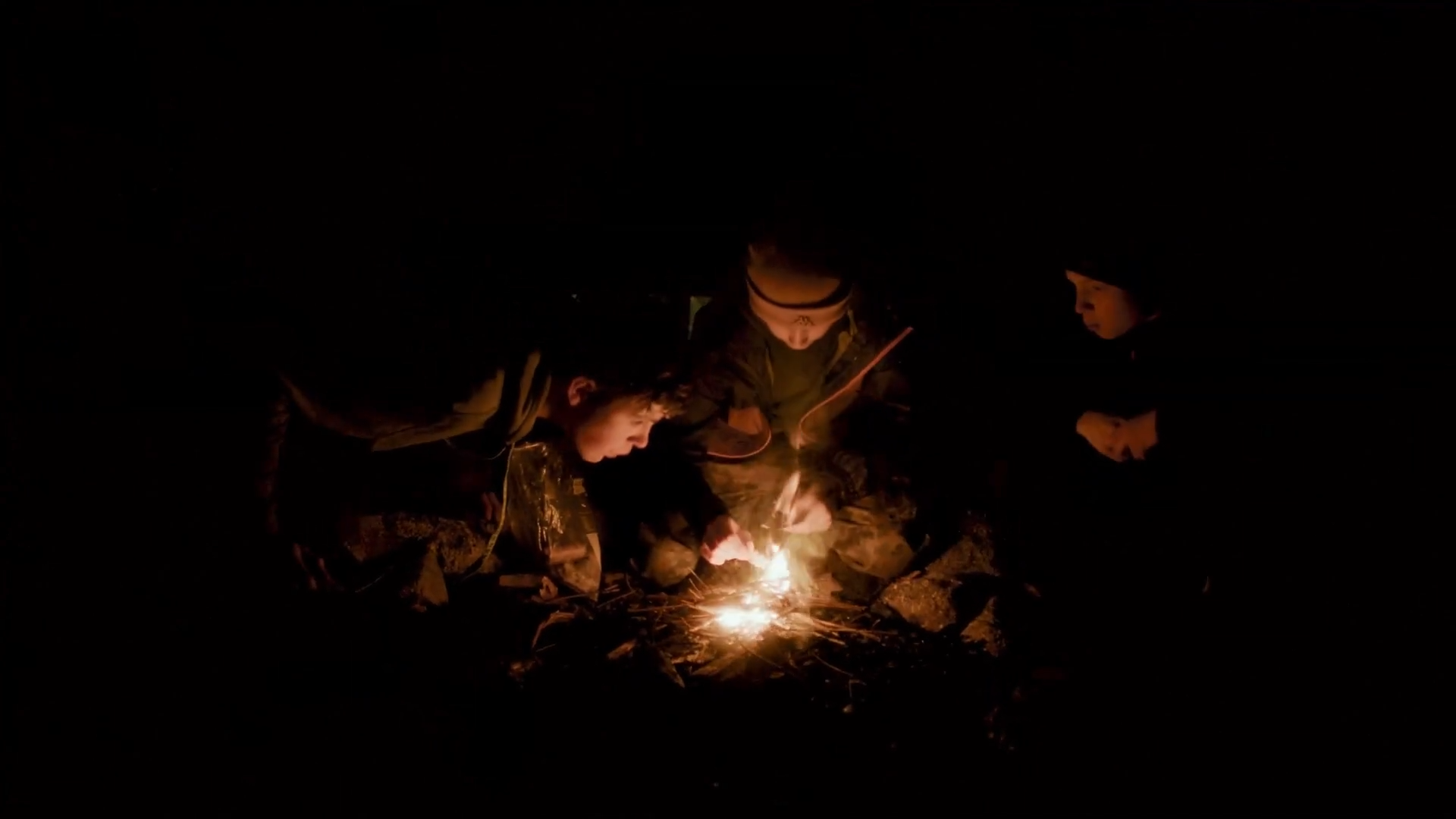 Gruppe sitzt am Lagerfeuer und reflektiert den Tag